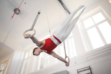 Yüzük holding, atlama ve spor salonunda sanatsal egzersizleri yapıyor genç sporcu adam 
