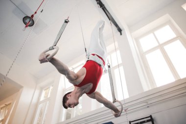 Yüzük holding, atlama ve spor salonunda sanatsal egzersizleri yapıyor genç sporcu adam 