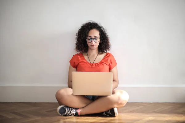 black young woman with laptop sitting on the floor