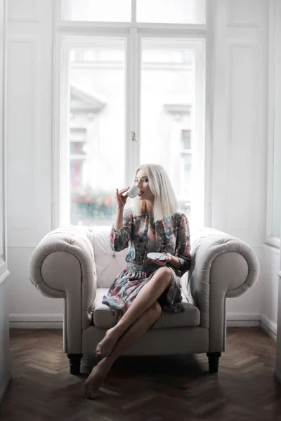 Ξανθό Πανέμορφο Μοντέλο Έχοντας Καφέ Κάθεται Στον Καναπέ — Φωτογραφία Αρχείου