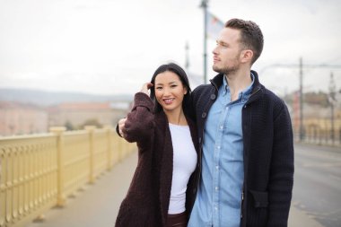 Genç mutlu çok kültürlü çift yürüyüş ve kendilerini kucaklayan