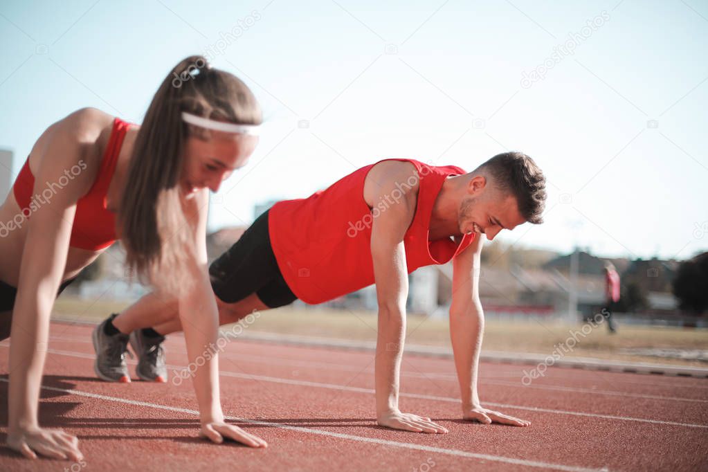 young athlete woman and man stretching and exercising before strating the contest