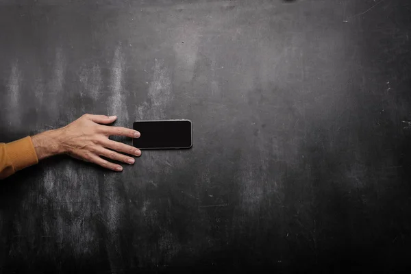 有人在黑板上触摸智能手机 — 图库照片