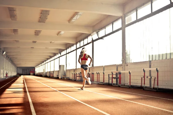 在体育设施中跑步的年轻女运动员 — 图库照片
