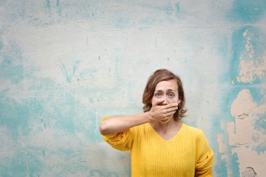 Sarı tshirt genç kadın ağzını kapsar