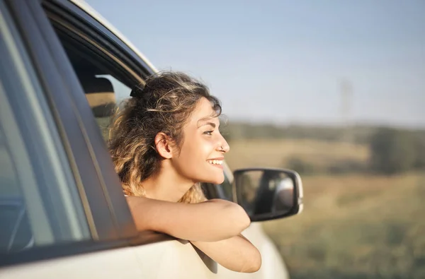 Νεαρή Όμορφη Γυναίκα Κοιτάζοντας Από Παράθυρο Του Αυτοκινήτου Και Χαμογελαστός — Φωτογραφία Αρχείου