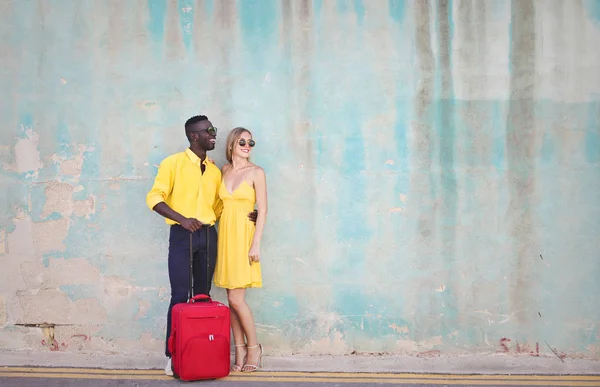 Jovem Casal Diversificado Com Mala Sorrindo Para Uma Parede — Fotografia de Stock