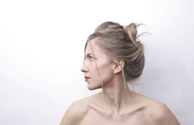 Beyaz duvarın önündeki sarışın kız.