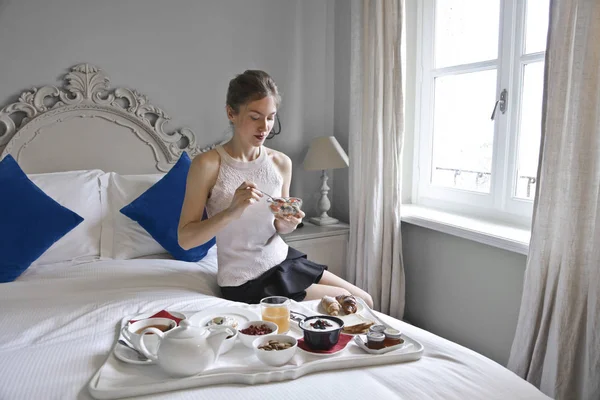 ブロンドの女の子はベッドの上で朝食を持っています — ストック写真