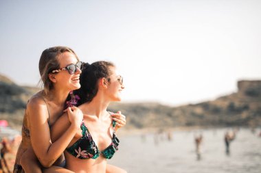 İki gülümseyen kız denize bakıyor.