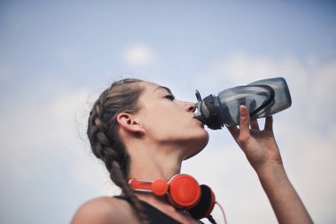 Kulaklıklı bir kız eğitim sırasında içiyor.