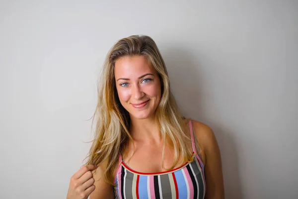 Glimlachend Blond Meisje Voor Een Witte Muur — Stockfoto