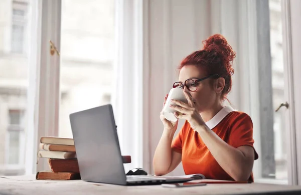노트북을 가지고 일하는 소녀가 커피를 마시고 있습니다 — 스톡 사진