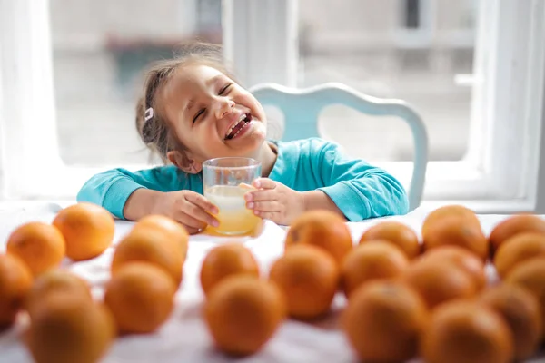 Mosolygó Kislány Gyümölcslevet Iszik Sok Narancslével Asztalon — Stock Fotó