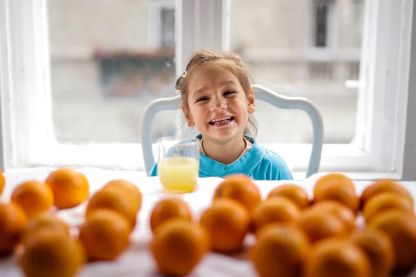 Mała Dziewczynka Wieloma Pomarańczami Pije Sok Pomarańczowy — Zdjęcie stockowe
