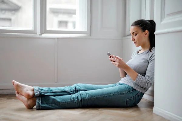 Uma Garota Está Mandando Mensagens Sentada Chão — Fotografia de Stock