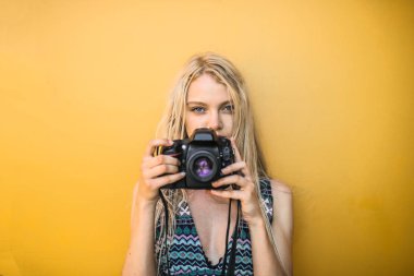 Blonde girl is taking a picture with a reflex clipart