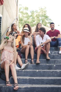 Bir grup arkadaş merdivenlerde oturuyor.