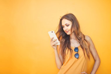 Sarı arkaplan önünde bir kız mesaj atıyor.