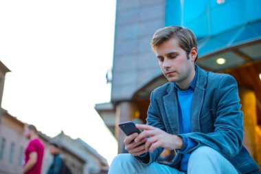 Şehirdeki bir bankta oturan bir çocuk mesaj atıyor.