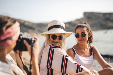 Bir grup kız sahilde fotoğraf çekiyor.