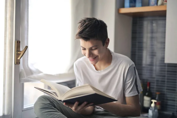 Έφηβος Διαβάζει Ένα Βιβλίο Πίσω Από Παράθυρο — Φωτογραφία Αρχείου