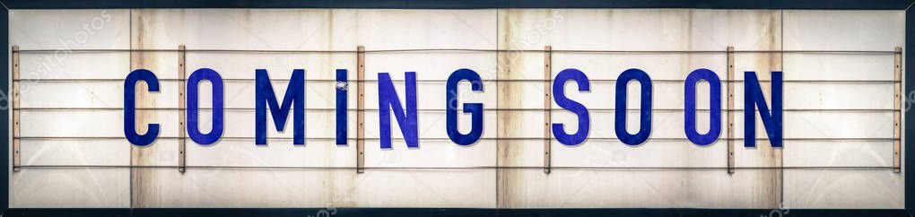 A Grungy Old Weathered Coming Soon Marquee Sign With Blue Letters