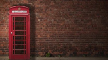 Geleneksel bir İngiliz telefon kutusu Gölgesini gün boyunca kırmızı bir tuğla duvarın üzerine bırakıyor