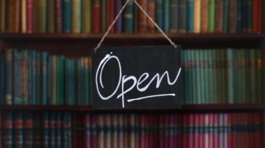 A Swinging Open Sign In The Window Of A Antique Book Store