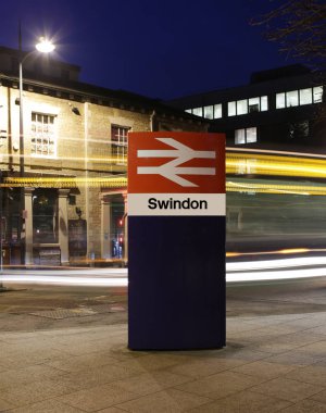 Swindon, İngiltere - 27 Aralık 2018: Swindon Tren istasyonu işareti bir geçen otobüs ışık yollar ile gece Wiltshire'deki/daki oteller