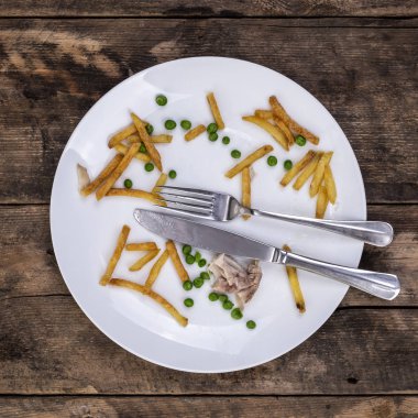 Artık cips bezelye ve tavuk yemek bir bıçak ve çatal bir rustik ahşap arka plan üzerinde plakalı