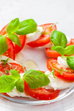 Olgun domatesli lezzetli caprese salatası ve taze fesleğen yapraklı mozzarella peyniri. İtalyan yemeği.