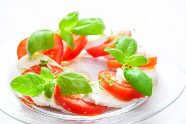 Olgun domatesli lezzetli caprese salatası ve taze fesleğen yapraklı mozzarella peyniri. İtalyan yemeği.
