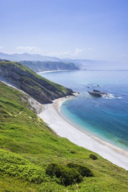 Cudillero, Asturias, İspanya 'daki Aguilar plajına bakan manzara, güzel turkuaz suları ve yeşil uçurumları vurguluyor.