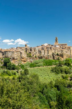Pitigliano, Tuscany, İtalya 'da bir ortaçağ kasabası, mavi gökyüzünün altında yeşil bir bitki örtüsüyle çevrili bir uçurumun üzerinde duruyor.