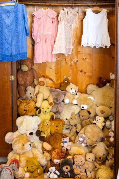 Винтажный деревянный шкаф полный плюшевых медведей и детских платьев висит, в Jaromerice над Rokytnou, Чехия
