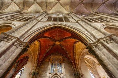 Low angle view of the impressive vaulted ceiling with ribbed vaults and red and gold painted details in Bourges Cathedral, France