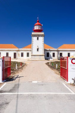 Güneşli bir günde Portekiz 'in Odemira şehrinde yer alan kırmızı ve beyaz kulesiyle Cabo Sardao Deniz Feneri' nin manzarası.