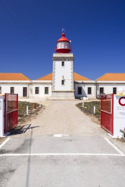 Güneşli bir günde Portekiz 'in Odemira şehrinde yer alan kırmızı ve beyaz kulesiyle Cabo Sardao Deniz Feneri' nin manzarası.