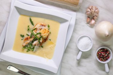 Lezzetli kremalı patates çorbası ızgara tavuk göğsü, parmesan talaşı ve taze roka ile süslenir.