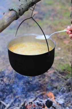 Ormanda kamp ateşi üzerinde turist kazana pişirme