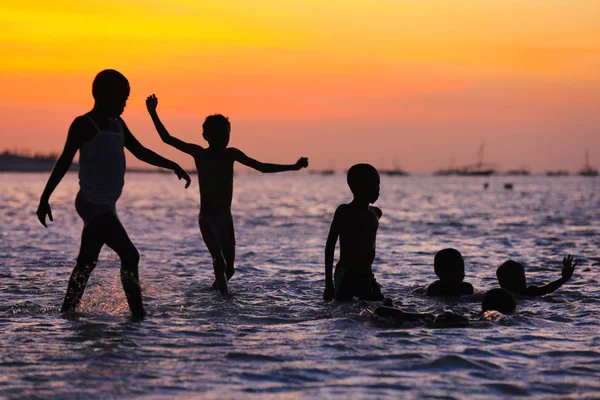 Gün batımında suda oynayan çocuklar — Stok fotoğraf