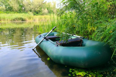 Yazın nehirde kürekleri olan şişme bir balıkçı teknesi.