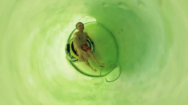 Человек скользит по трубе в аквапарке — стоковое видео
