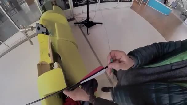 Человек стреляет из лука в помещении — стоковое видео