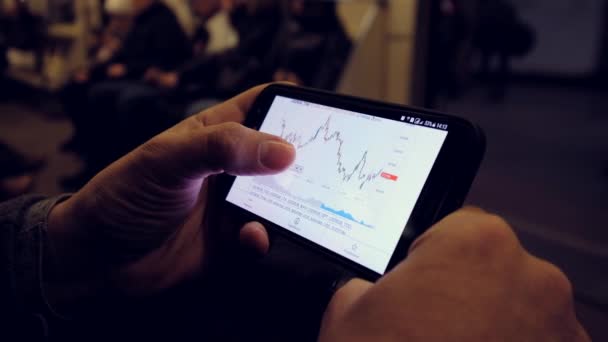 Kereskedő néz árfolyamdiagramok használ smartphone — Stock videók