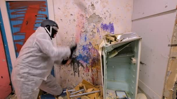 Зрілий чоловік знищує старий холодильник на санях у руїнах — стокове відео