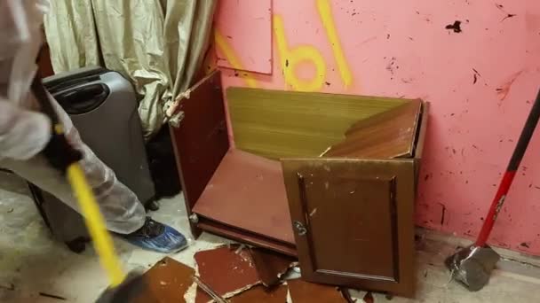 유적에서 쇠 망치에 의해 오래 된 냉장고를 파괴 하는 성숙한 남자 — 비디오