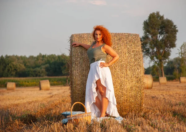 Femme rousse posant sur le terrain près d'une meule de foin — Photo