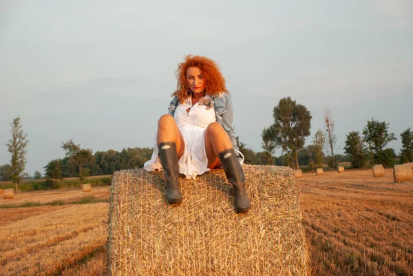 Femme rousse posant sur le terrain près d'une meule de foin — Photo